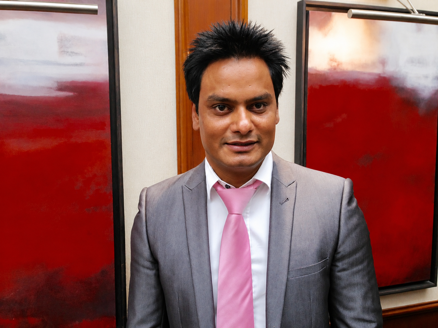 Naz wearing a grey suit and pink tie